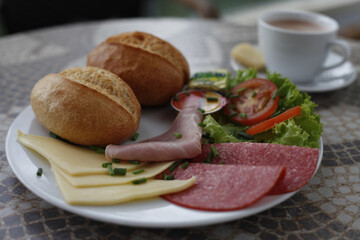 Delicious breakfast plate with bread, cheese, meat, and coffee