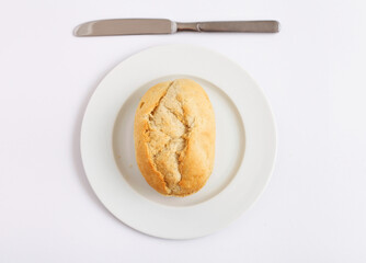 Bread roll on a white plate with a butter knife