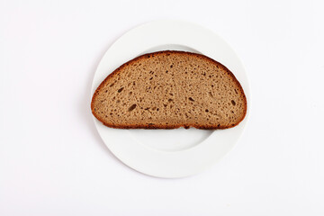 A slice of brown bread on a white plate against a white background.