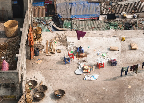 Aerial view of a rooftop scene with a person surrounded by everyday objects under the open sky, creating a sense of intimate urban life, Dhaka, Dhaka Division, Bangladesh.