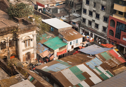 Aerial view of tin roofs in variegated hues of blue, green, and red contrast with the weathered brick buildings, Dhaka, Dhaka Division, Bangladesh.