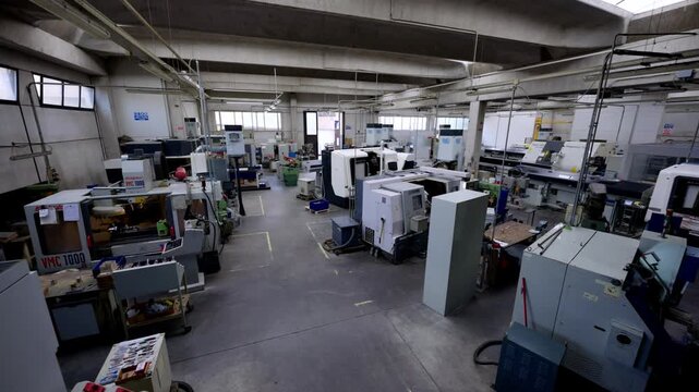 Wide shot of a clean, modern machine shop or manufacturing factory floor with several CNC machines, highlighting high-tech automation and precision engineering