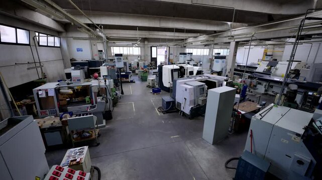 Wide shot of a clean, modern machine shop or manufacturing factory floor with several CNC machines, highlighting high-tech automation and precision engineering