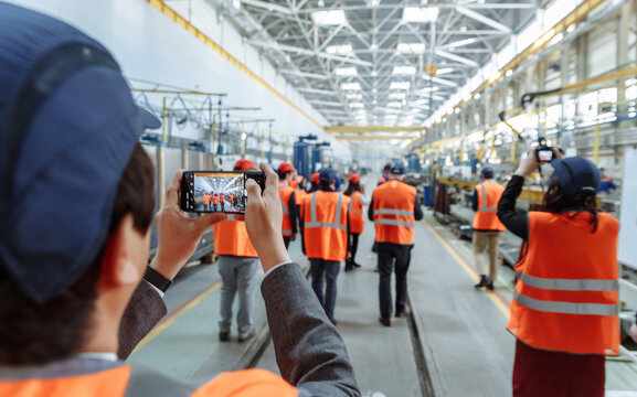 Documenting progress. A group in safety gear captures images of a modern factory floor, symbolizing innovation, industrial tourism, training, or factory tours. Perfect for business and education