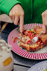 A girl cuts a croissant with filling with a knife and fork
