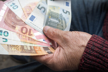 Euro banknotes in the hands of a senior.
