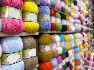 colorful threads for sale. row of  yarn balls displayed on shelves in craft store, knitting and...