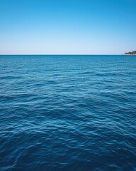 Calm blue ocean meets cloudless sky. Small island on horizon