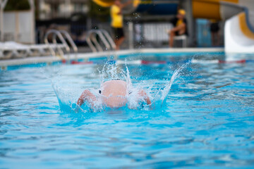 The boy bathes, swims and dives in the pool. Summer vacation and travel concept. Peaceful tropical summer holiday, travel, relaxation, summer vacation,
