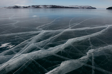 Cracked frozen lake surface with mountain view.