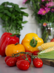 Fresh Tomatoes, Corn and Bell Peppers with Flowers in Kitchen Background