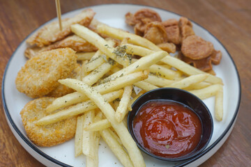 A delicious plate of golden fried snacks with ketchup and crispy fries on a wood background
