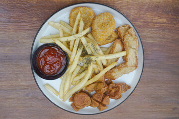 A delicious plate of golden fried snacks with ketchup and crispy fries on a wood background