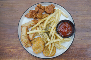 A delicious plate of golden fried snacks with ketchup and crispy fries on a wood background