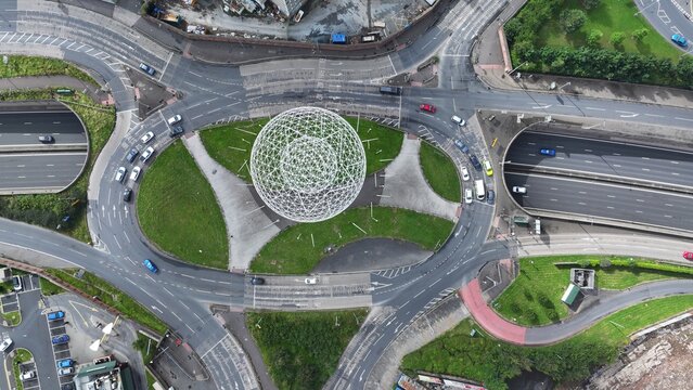 Aerial view of the Rise sculpture contrasts with the surrounding roadways, a modern art piece amidst the urban sprawl, Belfast, Northern Ireland, United Kingdom.