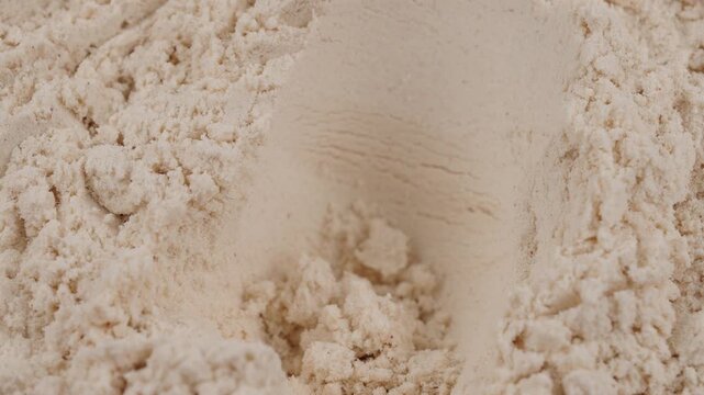 Take out a measuring spoon filled with white protein powder. Close-up of sports nutrition supplement for fitness, healthy diet, muscle recovery concept. Vanilla whey powder. Bodybuilding gym lifestyle