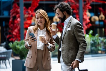 Business people discussing during coffee break using smartphone