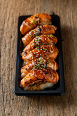 Freshly Grilled Salmon Sushi on a Black Plate with Wood Background