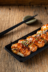 Delicious Salmon Sushi with Sauces on a Black Plate and Wooden Table