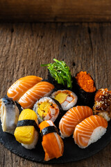 Assorted Fresh Sushi on Black Slate Plate Against Wooden Background