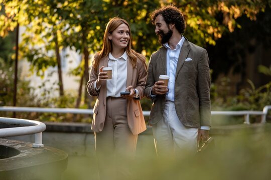 Business people walking and talking during coffee break outdoors - Powered by Adobe