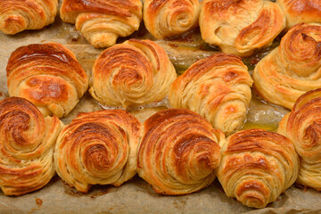 A  close-up of a baking sheet filled with freshly baked, golden-brown croissants and pastries