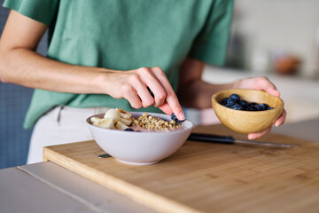 Portrait of a young woman preparing and eating breakfast, drinking juice in the kitchen at home