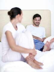 Fototapeta premium Happy man, woman and chat in bedroom with pyjamas, conversation and bonding for relationship connection. Couple, people and trust together with discussion, marriage and love in apartment home.