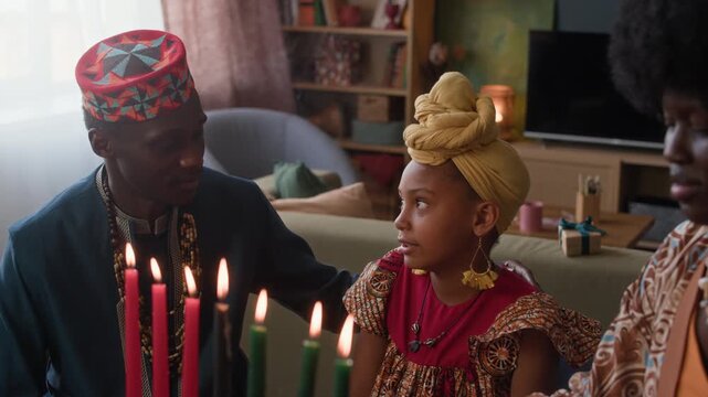 African American family of three enjoying heartfelt conversation at table beside glowing Kwanzaa candles, honoring tradition, unity, and cultural pride