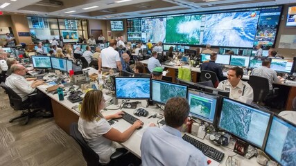 Command Center: A busy command center teems with dedicated individuals, their eyes glued to computer screens displaying real-time data and analytics. - Powered by Adobe