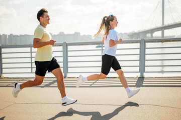 Fototapeta premium Running along the riverside with friends during a sunny afternoon workout