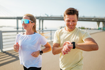 Couples enjoying a morning jog by the river under a clear sky