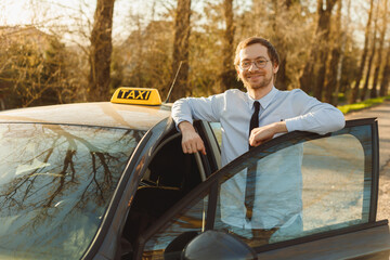 Portrait of smiling caucasian taxi driver near car, looking at camera.