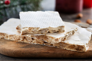 Traditional Christmas sweet, pieces of delicious almond nougat on wooden table( turron duro)