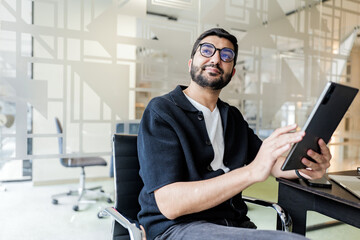 Man using tablet while seated in modern office setting with glass walls