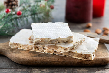 Traditional Christmas sweet, pieces of delicious almond nougat on wooden table( turron duro)