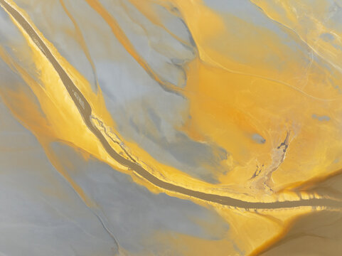 Aerial view of a winding stream carving through a landscape painted in hues of gold and gray, creating a mesmerizing tapestry of nature's artistry, Minas de R&Atilde;&shy;otinto, Andalusia, Spain.