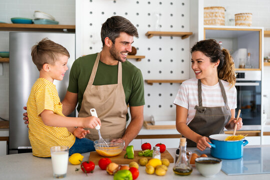 A happy family is cooking together in a bright kitchen, showing joy, teamwork and quality time - Powered by Adobe