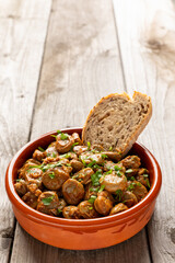 Tapas bowl with vegan version of Spanish habas con jamón and a slice of bread. Unpeeled fava beans cooked with garlic, onions, smoked paprika, white wine, and olive oil.
