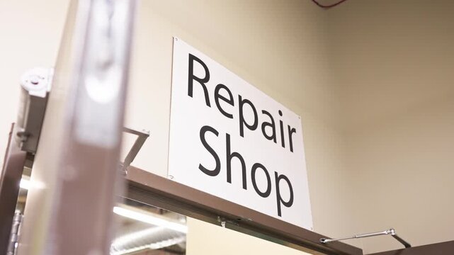 Gimbal shot shows white REPAIR SHOP sign over the workshop&rsquo;s double doors