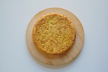 Homemade Spanish omelette (tortilla de patatas)  placed on a wooden plate seen directly from above 