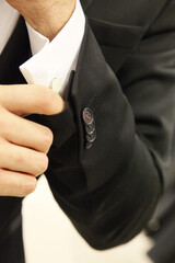 Man in a black suit adjusting his cufflink