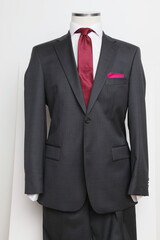 Elegant charcoal suit on a mannequin with a vibrant burgundy tie.