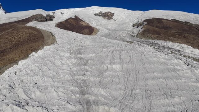 Aerial view of the serene Muztagh Glacier, a landscape of stark whites and contrasting browns under a crisp blue sky, Xinjiang, China.