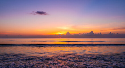 Obraz premium Vivid Sunset Sky Over Calm Ocean Water and Gentle Shoreline A stunning, low-angle seascape capturing the vibrant, colorful beauty of sunrise or sunset over the ocean 