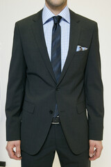 Man in a dark suit with a blue checkered shirt and striped tie