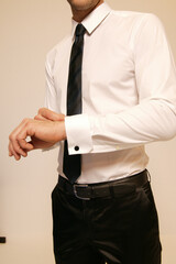 Man in formal attire adjusting his cufflink
