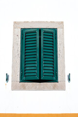 The scene captures Mediterranean or tropical wooden shutters on windows charm , with warm sunlight. Ideal for travel, architecture, and lifestyle themes.