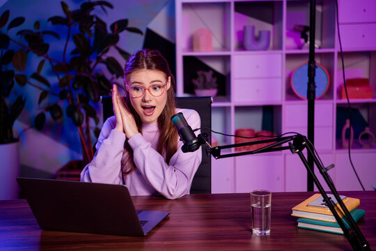Popular female content creator recording a podcast with professional equipment in a stylish home office at night