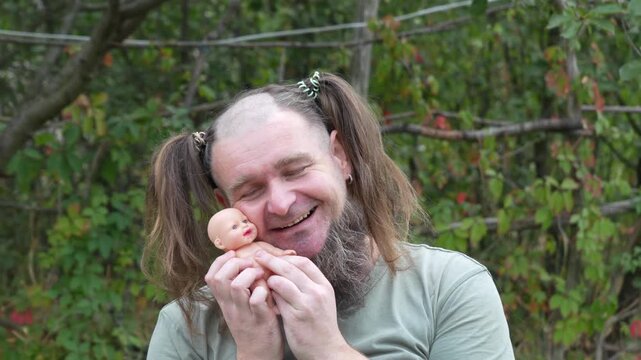 Funny bearded man with pigtails holding and playing with doll outdoors. Humorous cosplay concept, comic character, perfect for meme or parody video at 50 FPS.